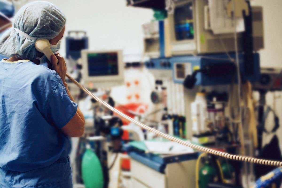 A person wearing scrubs talks on a hospital phone