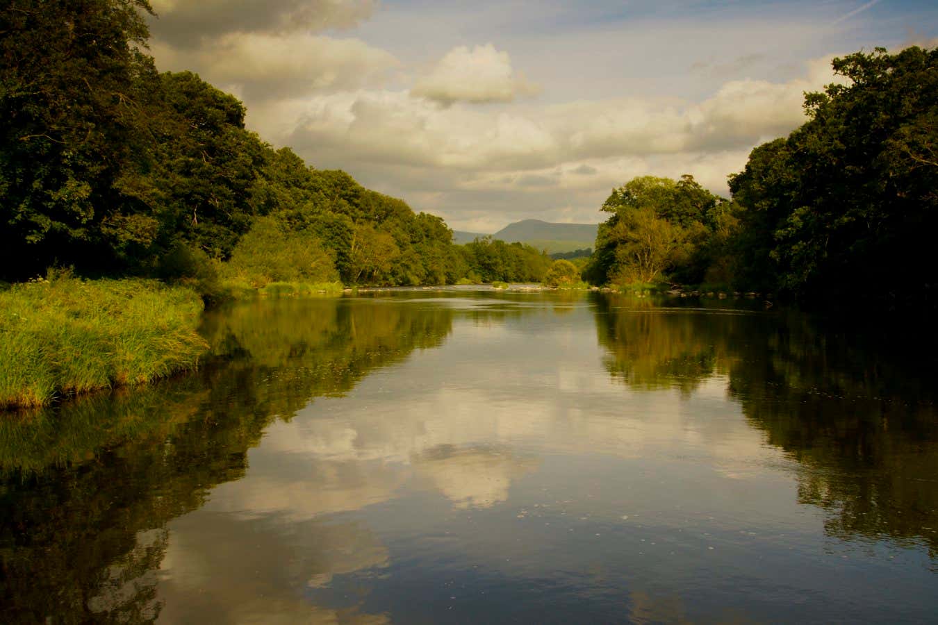 Cloud and trees reflections on river Wye with Black mountains background.