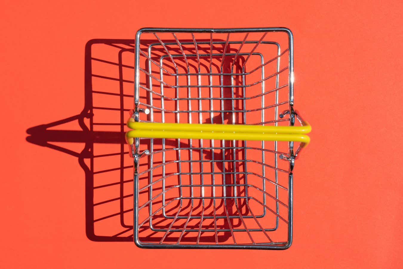 steel supermarket basket with hard shadow on colored background. High quality photo