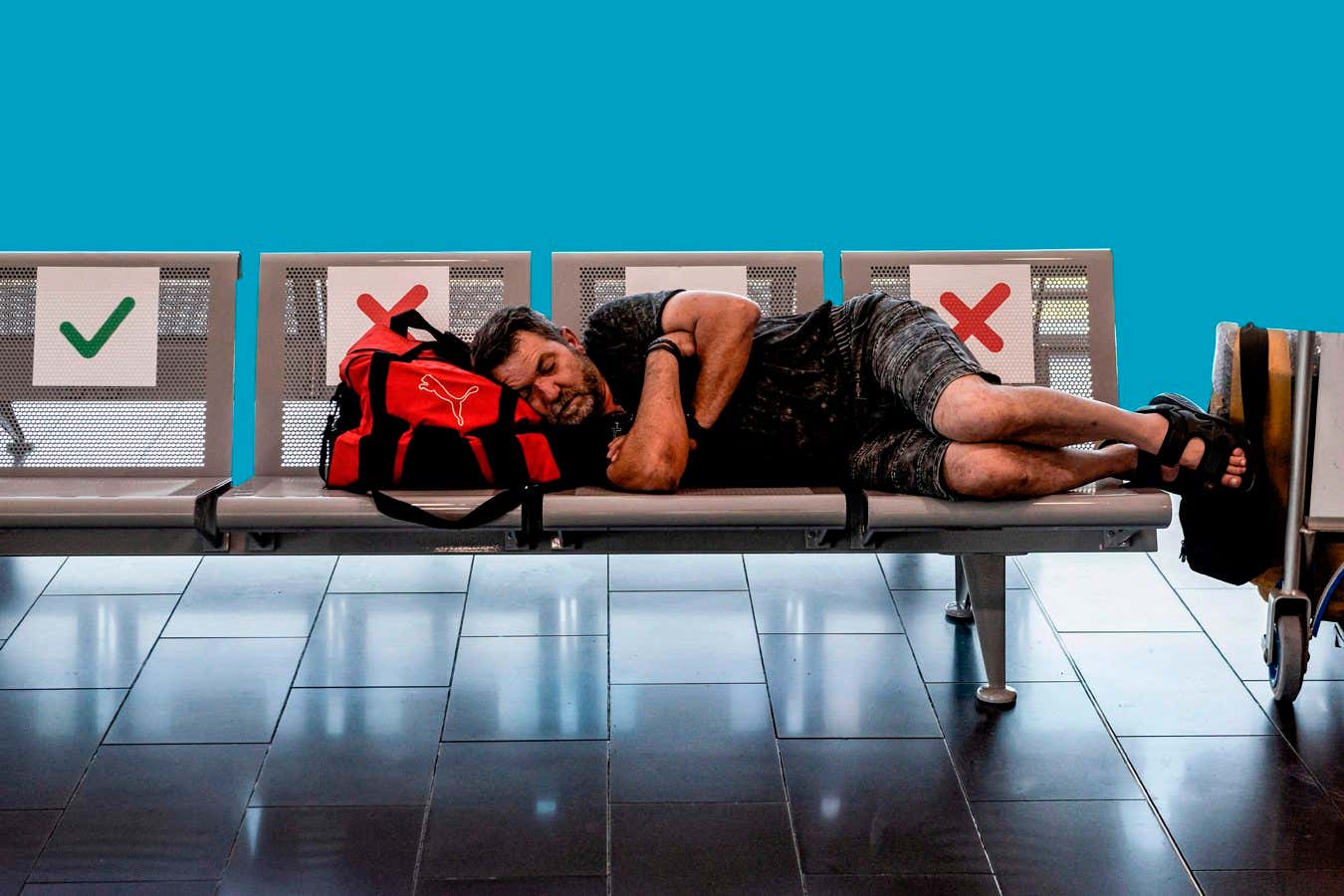 A traveller sleeps on a bench with a suitcase at Cyprus' Larnaca International Airport on June 9, 2020. - Cyprus opened back up for international tourism on June 9, with airports welcoming visitors after an almost three-month shutdown due to the novel coronavirus pandemic, with a bold plan to cover health care costs for visitors. (Photo by Iakovos Hatzistavrou / AFP) (Photo by IAKOVOS HATZISTAVROU/AFP via Getty Images)