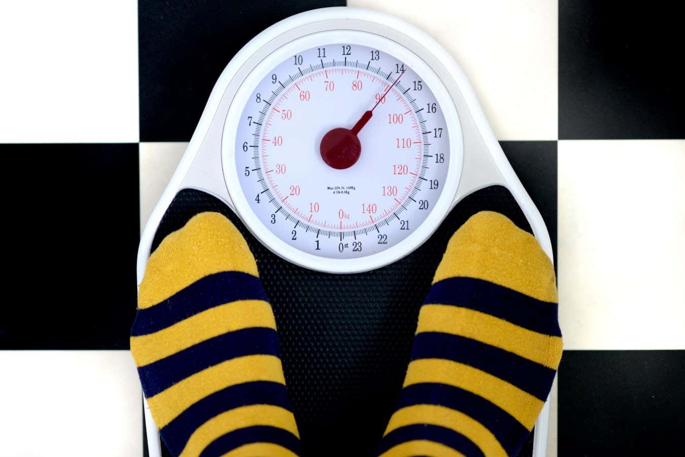 G0Y3BW Bathroom scales on checkered floor