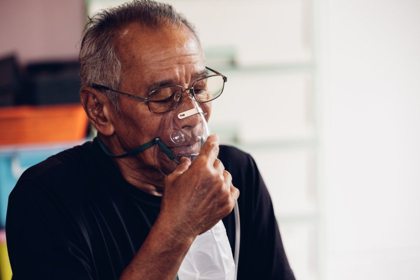 Older man wears a respiratory mask over his mouth